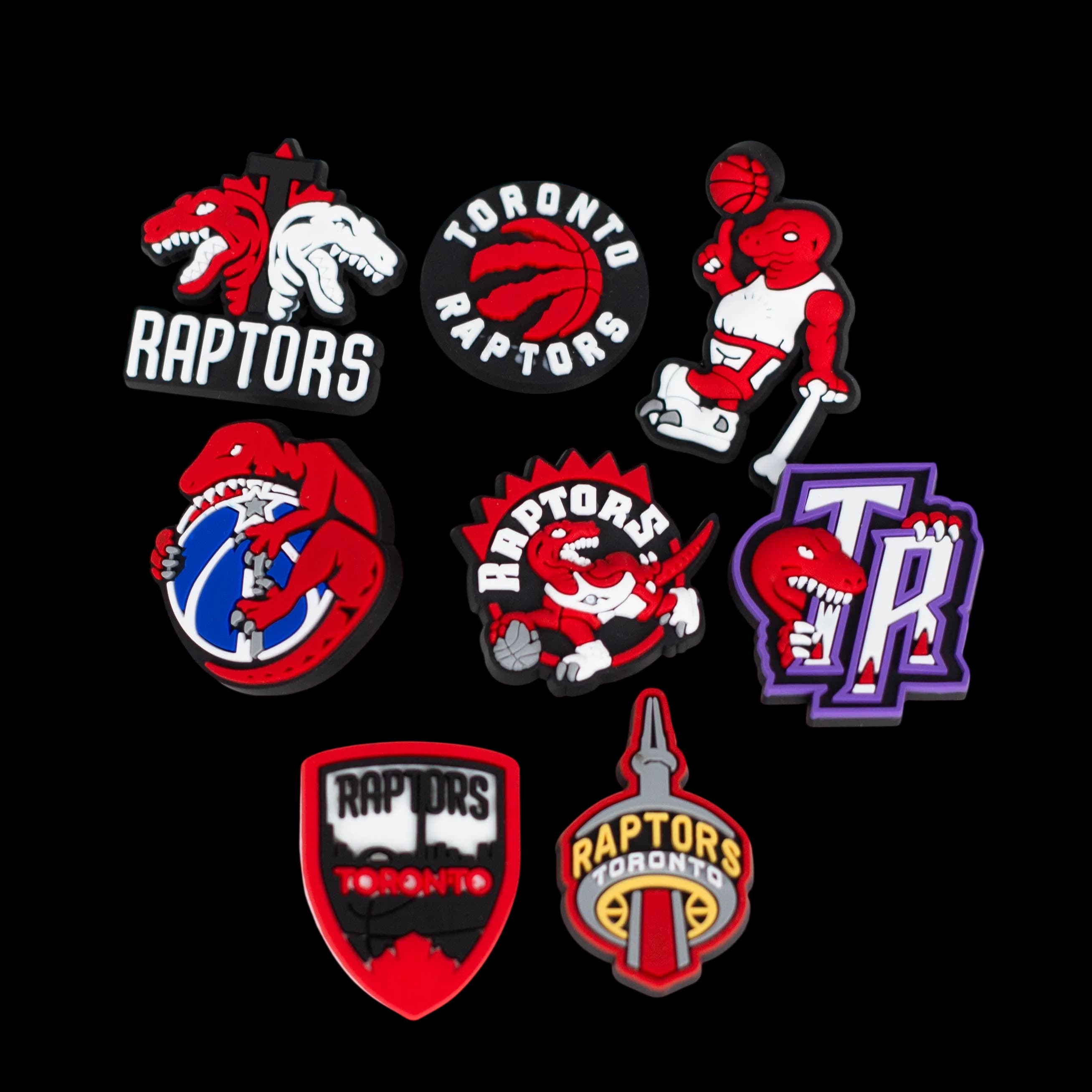 Collection of eight Toronto Raptors-themed Crocs charms featuring red dinosaur mascots, basketball logos, and team graphics in red, black, and purple