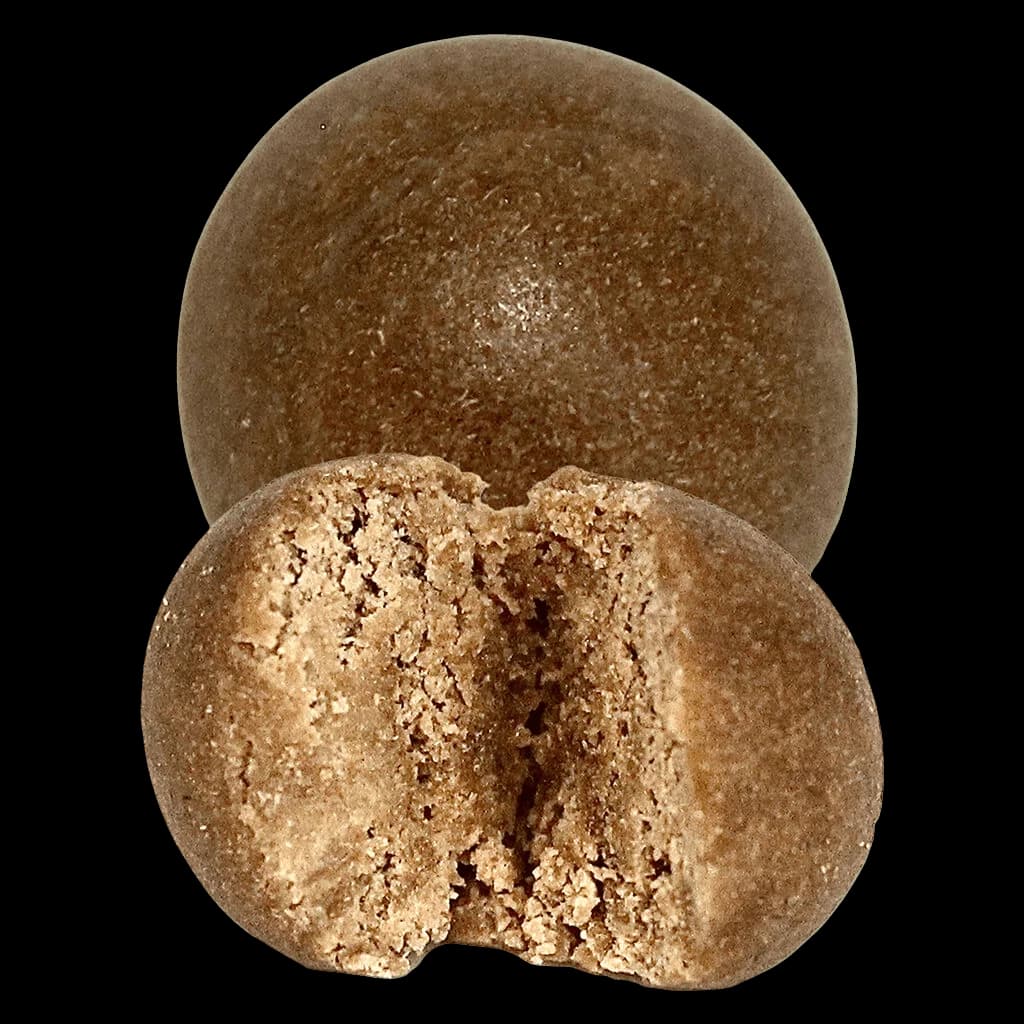 Haschich en boule temple fruitée Curado, deux sphères à texture friable et de couleur brun sable