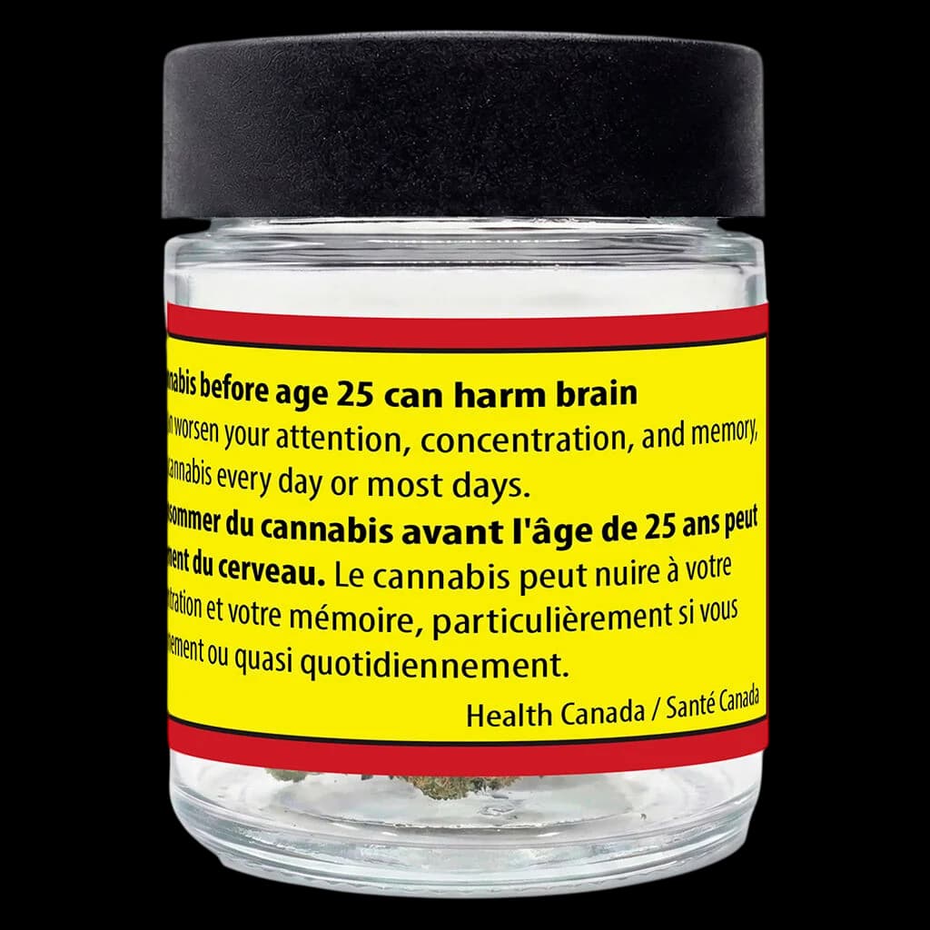 Glass jar with black cap containing cannabis flower, yellow and red Health Canada warning label visible