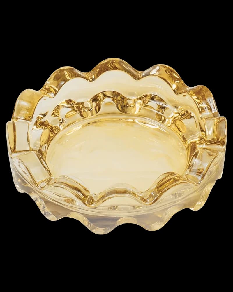 Golden glass concentrate container with wavy rim and pale yellow cannabis oil or concentrate inside