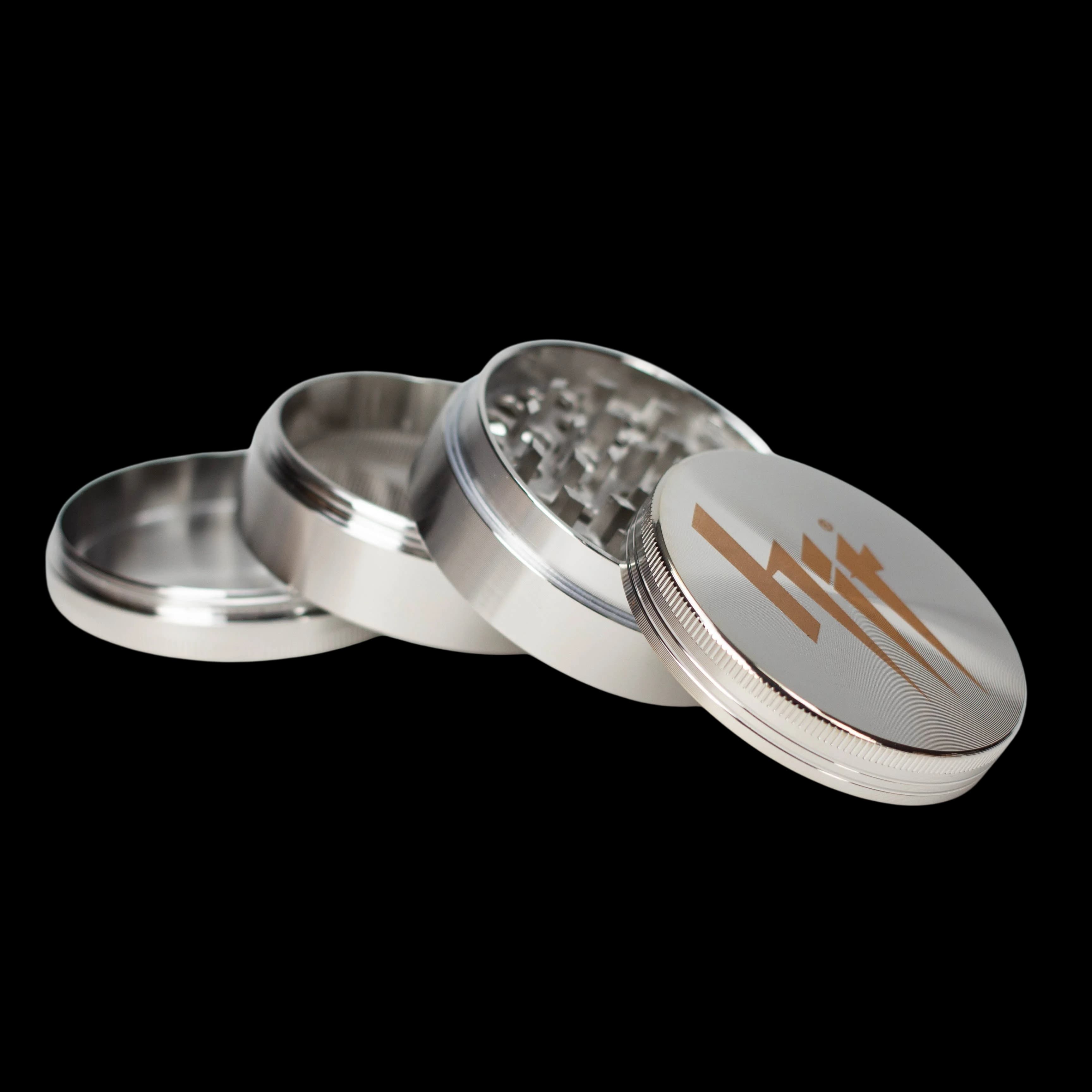 NIBO Distribution HIT 63mm four-part metal grinder with silver aluminum body and brown logo on top cap, showing open chambers and grinding teeth
